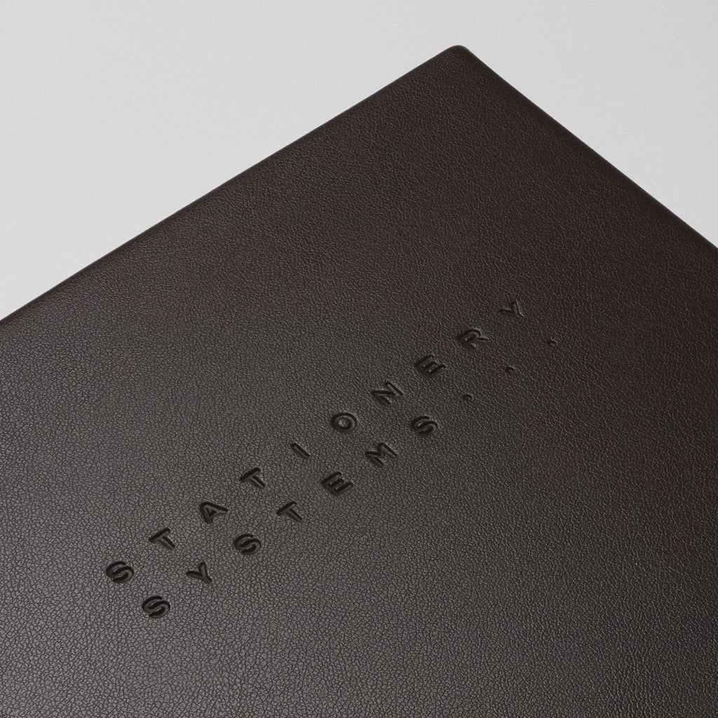 Dark brown notebook with embossed text on a beige background