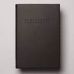Dark brown notebook with 'Stationery Systems' branding on a beige background
